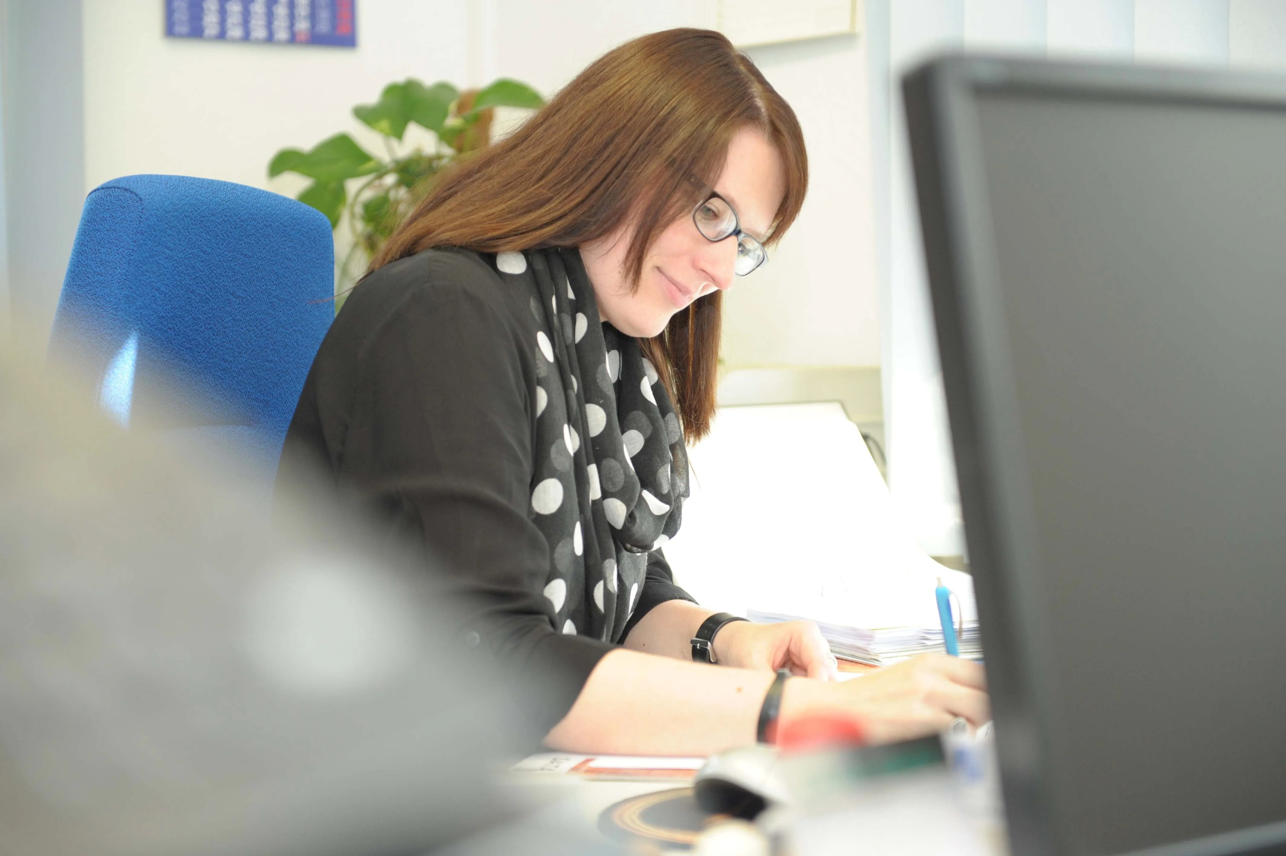 Frau arbeitet an Laptop am Schreibtisch.