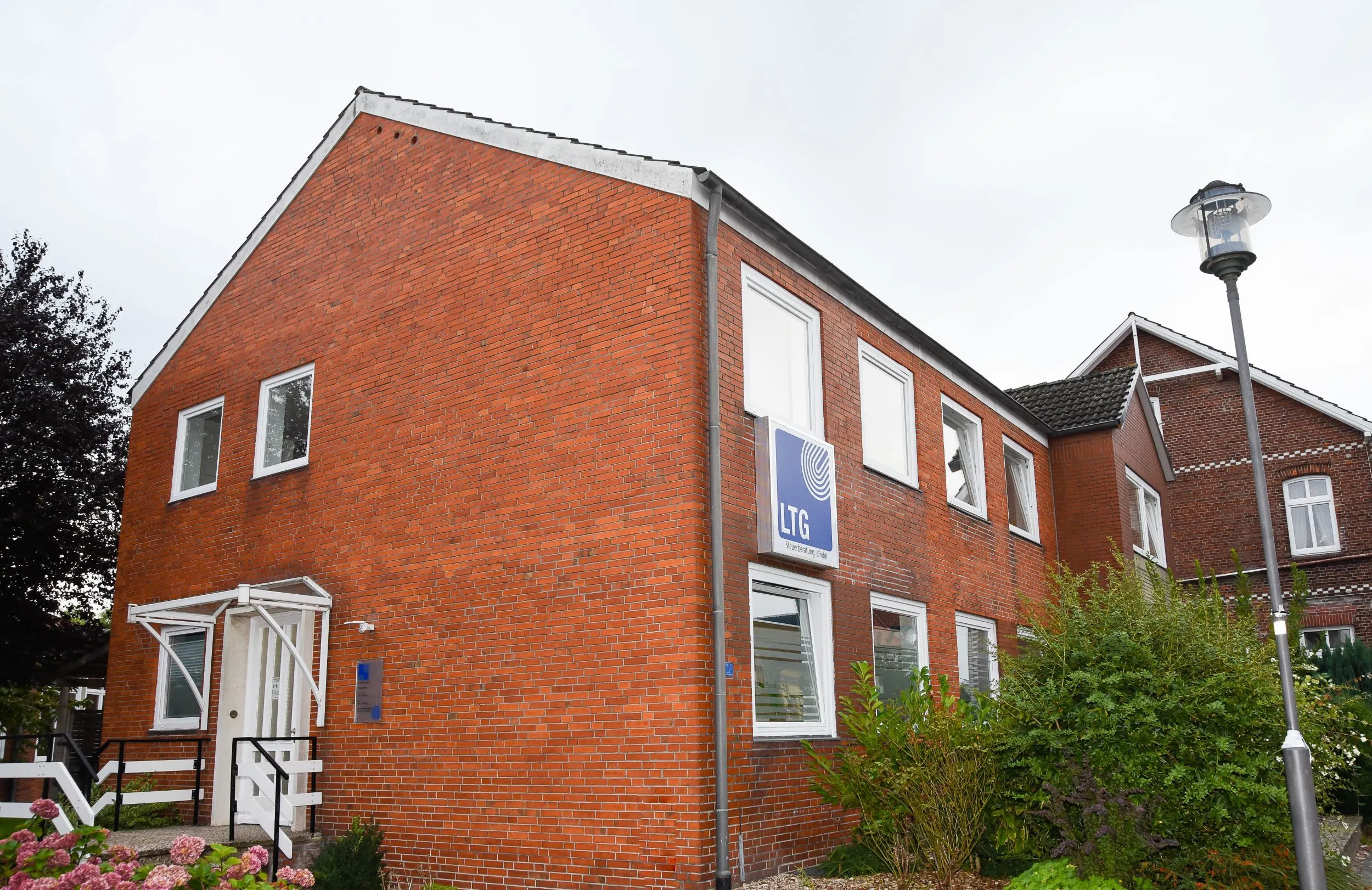 Rotes Backsteingebäude mit Bäumen im Vordergrund
