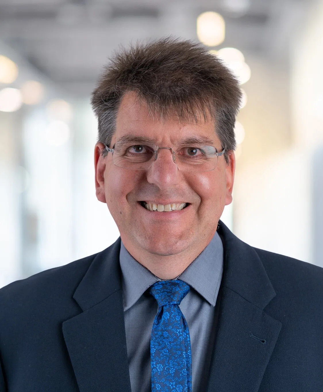 Mann im Anzug mit Krawatte lächelt in die Kamera
