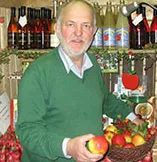 Mann mit grünem Pullover steht vor Obst- und Gemüseregal
