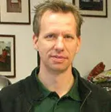 Porträt eines Mannes vor einer Bilderwand
