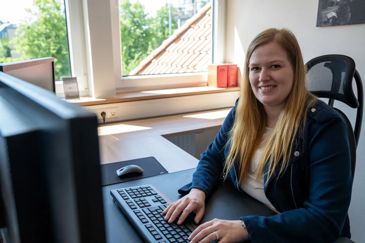 Junge Frau arbeitet am Laptop, lächelt
